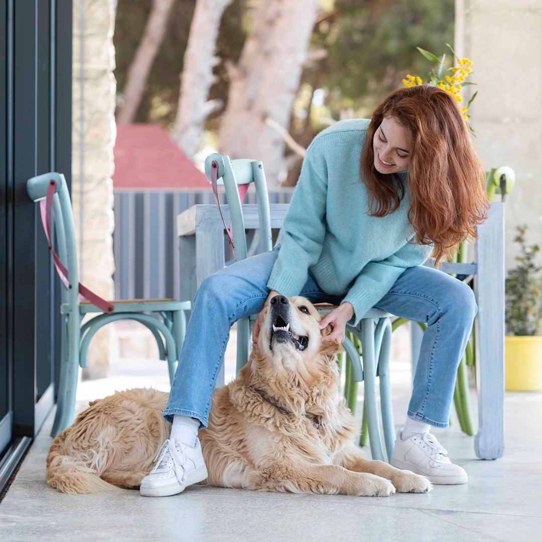 a woman gently pets a dog while sitting on a patio